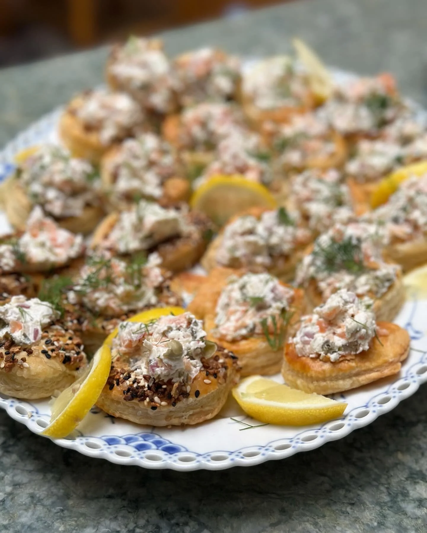 Small savory salmon tarts arranged on a white serving plate with lemon wedges