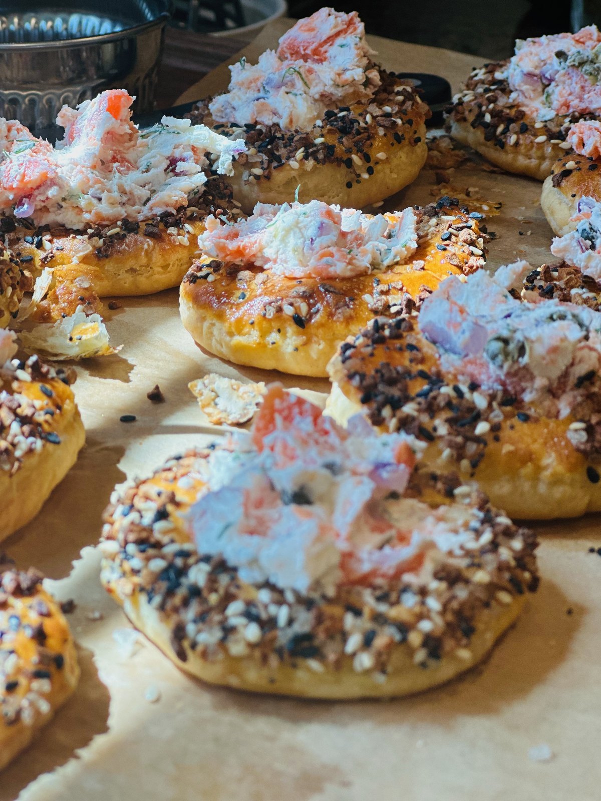 Everything bagels topped with salmon salad, arranged close together on parchment