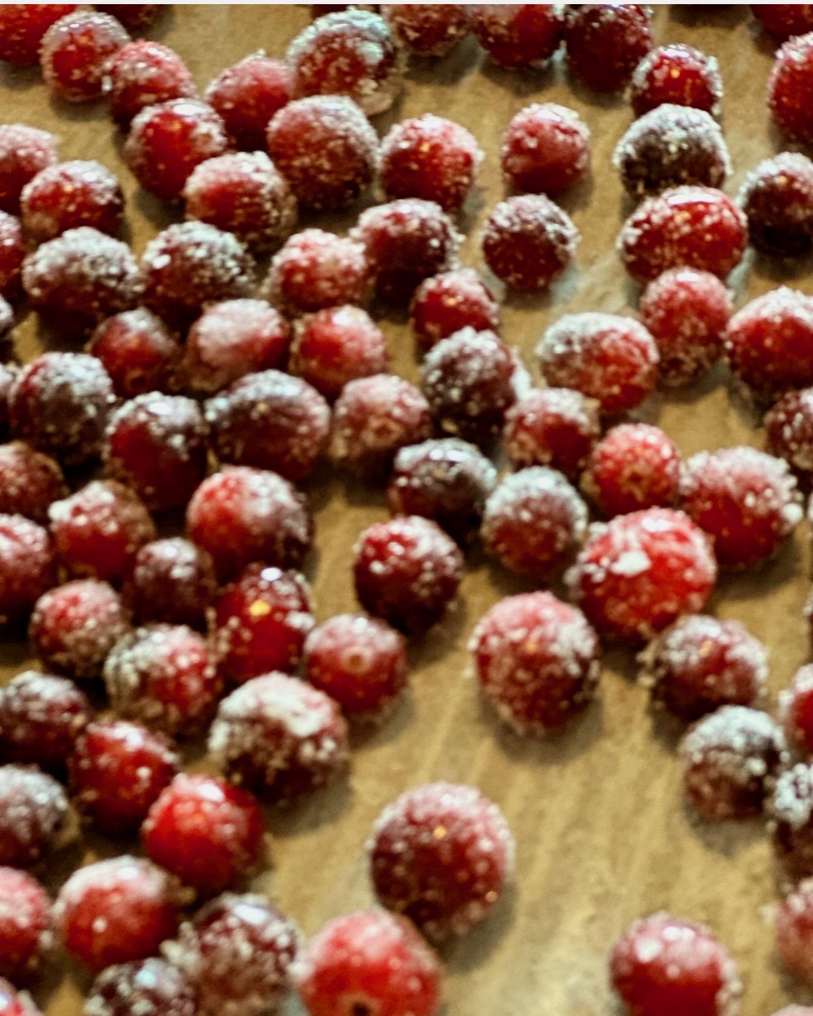 Red cookies dusted with powdered sugar cooling on a parchment-lined baking sheet