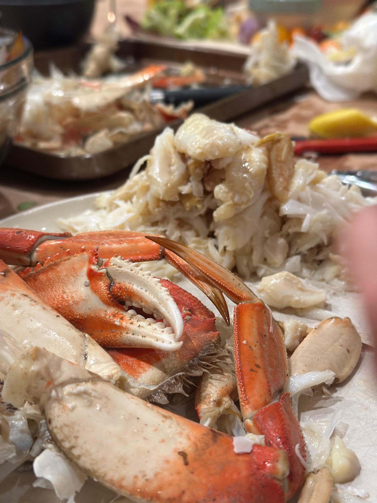 Picked crab meat and bright red crab shells piled on a plate at a lively table
