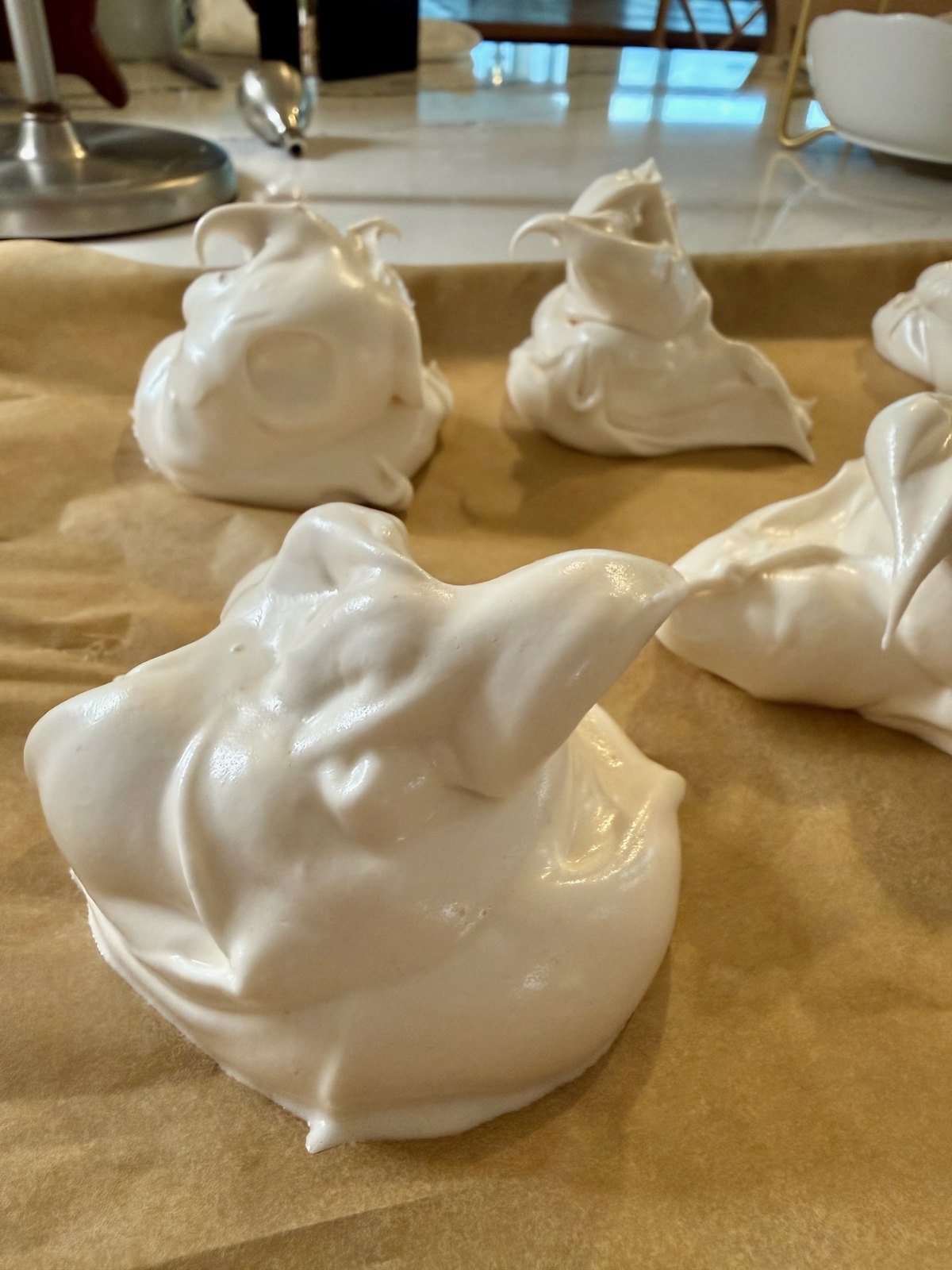 Freshly piped meringues on a parchment-lined baking sheet